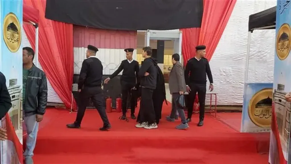 رجال الشرطة يساندون مسنة للإدلاء بصوتها في إحدى اللجان الانتخابية بإمبابة